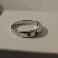 Silver ring with purple gemstones on a white background