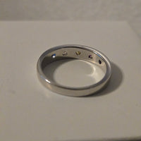Metallic ring with engraved symbols on a beige background